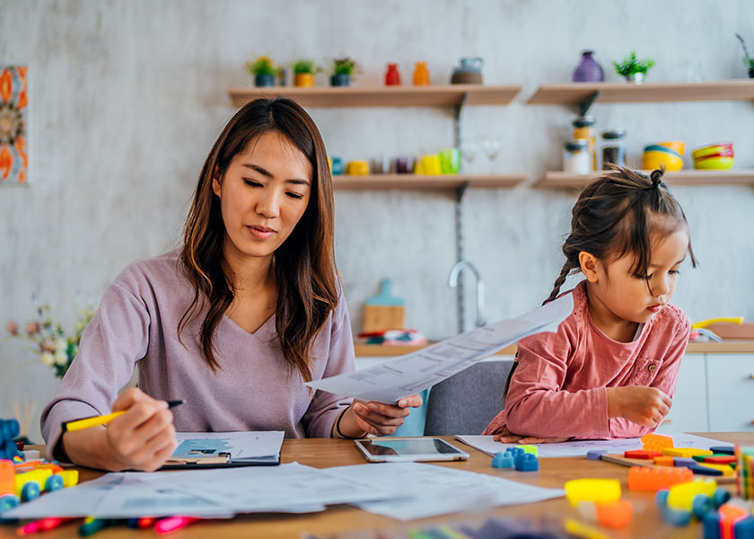 Woman at home reviewing bills and using a calculator to plan family finances